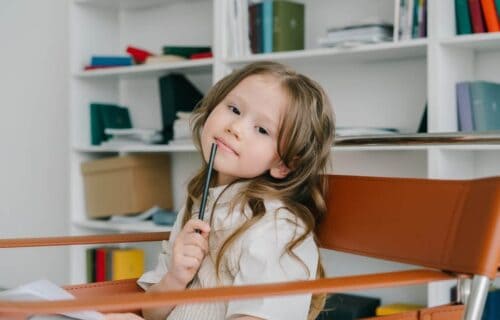 Enfant pensif avec stylo, exprimant ses émotions et sa réflexion.